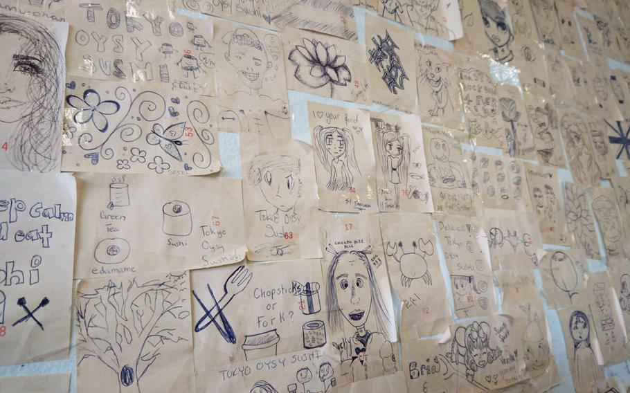 A collage of customer drawings decorates the Tokyo Oysy Sushi restaurant in the village of Beck Row, England. The friendly staff leaves a pen and small sheets of paper for customers to doodle on while they wait.