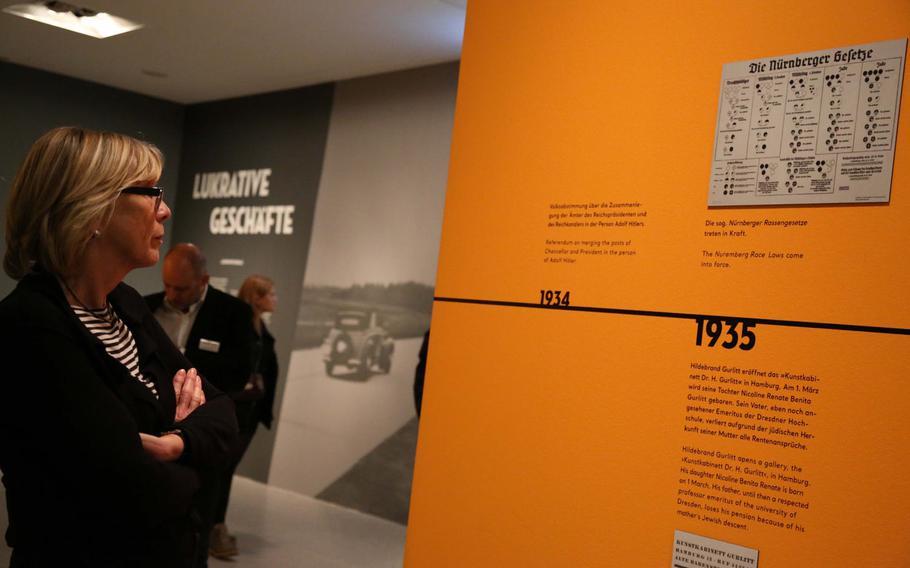 A visitor to an exhibit of paintings from the collection of Hildebrand Gurlitt in Bonn, Germany, reads about the Nuremberg Laws, which classified Germany's population by race. Much of Gurlitt's collection was made up of works stolen from Jews or sold by them under duress.