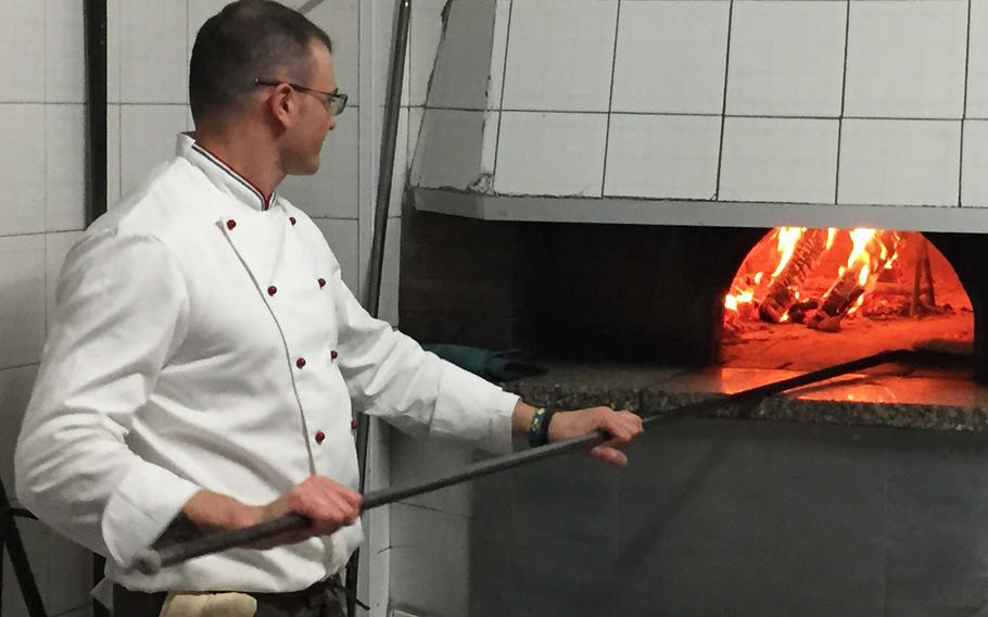 A cook bakes pizzas in a wood-fired oven at Pizzeria Trattoria Lucrino in Pozzuoli, Italy. The restaurant offers a diverse selection of pizzas and seafood at a modest price. 