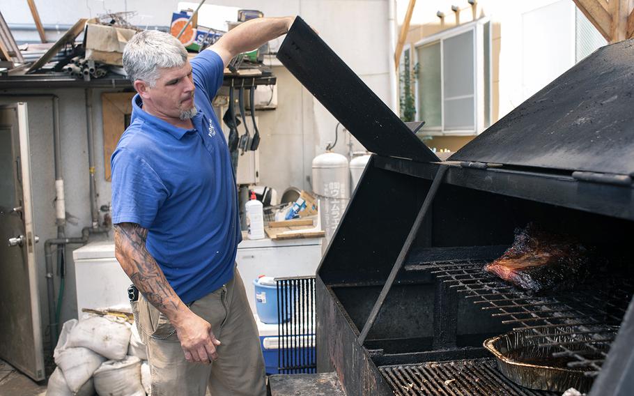 Phil Azevedo, the proprietor or Rib House Bar and Grill, inspects the meats smoking outside his restaurant in Iwakuni.