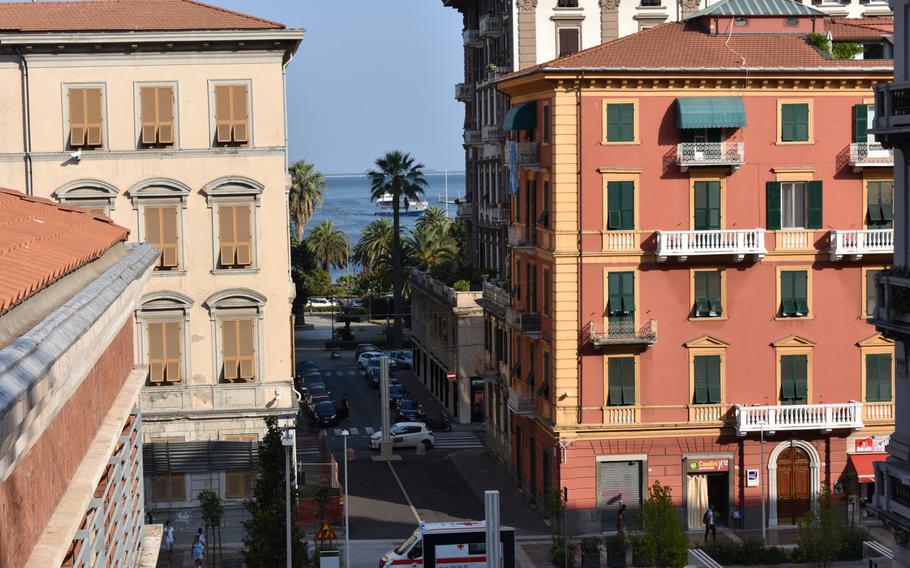 A view of the harbor through buildings in La Spezia, Italy. The hilly city has multiple elevation changes, offering vantage points of the spectacular surrounding scenery.