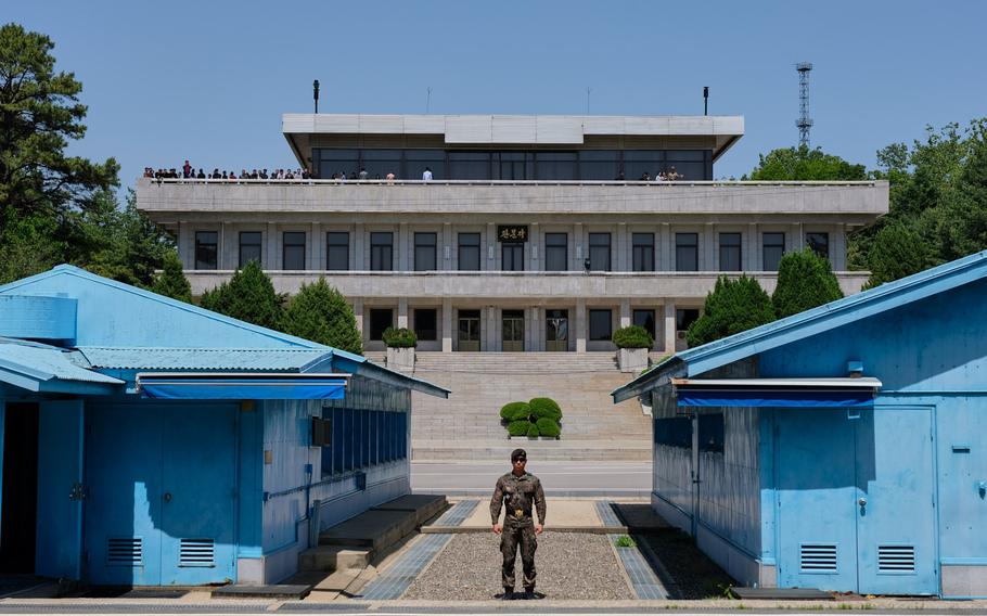A South Korean soldier stands in front of the Military Demarcation Line in the Joint Security Area, May 29, 2019. A North Korean tour group can be seen on the roof of the building in the background. 