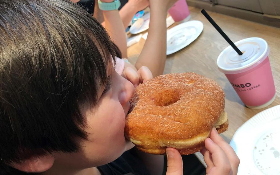 A boy bites into an enormous Cinnamon Sugar doughnut at Dumbo Doughnuts and Coffee in Tokyo's Azabujuban neighborhood.