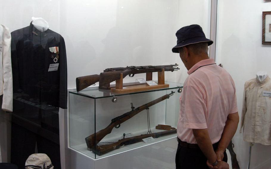 An old Japanese man looks at the weapons used by Japanese soldiers during the war.