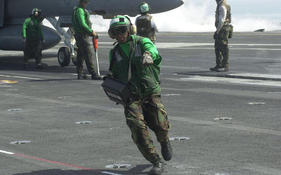 A member of the crew of the USS George Washington signals to his counterparts as an aircraft prepares to take off during the Invincible Spirit exercise on Sunday in the Sea of Japan.  