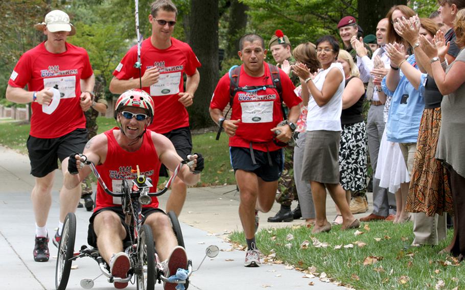 From left to right, British Staff Sgt. James Mezzoni-Dawson, British Cpl. Lloyd Fenner, U.S. Gunnery Sgt. Charles Padilla, and British Color Sgt. Damian Todd on the hand bike, run past the British embassy in Washington Tuesday as part of the “Gumpathon,” a 3,530-mile run across the United States.