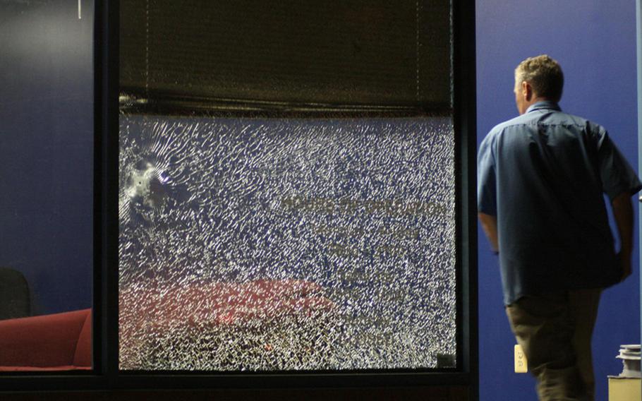 A bullet hole and shattered glass can be seen as an FBI official walks into the Marine Corps Recruiting Center at Sully Place Shopping Center in Chantilly, Va. 