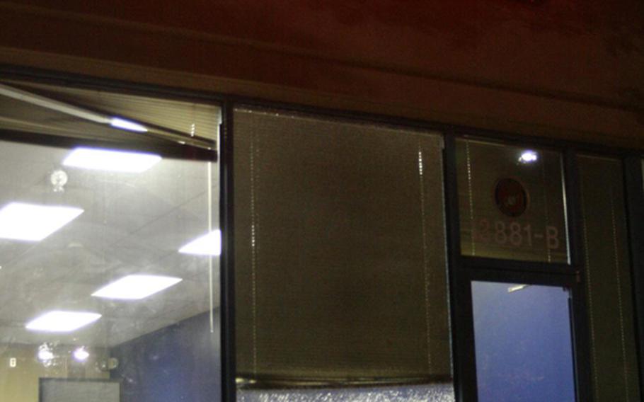 A bullet hole and shattered glass can be seen as an FBI official walks into the Marine Corps Recruiting Center at Sully Place Shopping Center in Chantilly, Va. 