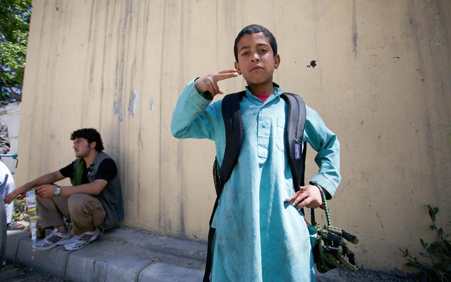 Basir, 10, sells bracelets to coalition troops outside the International Security Assistance Force headquarters in Kabul. Squatting on the curb is Safiullah, 20, a phone card salesman who got Basir started in the business.

