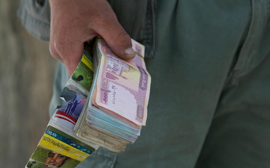 Safiullah holds a stack of cash and phone cards as he waits for Afghan workers from coalition bases and nearby embassies to leave work. Some days he makes money, some days he does not.
