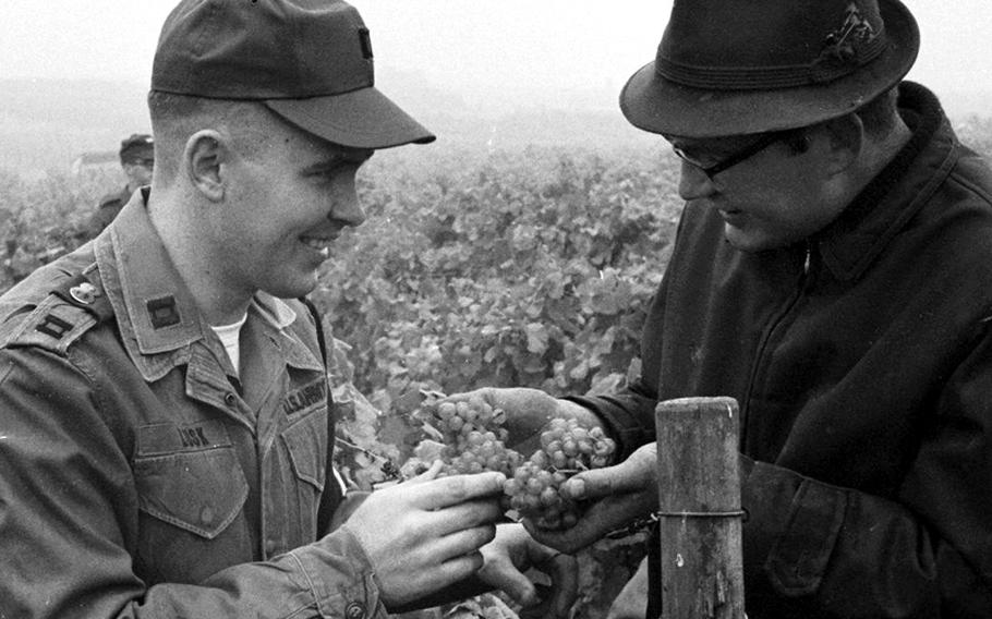 U.S. Army Capt. Fred Lusk and vineyard owner Peter Nissen inspect some grapes.