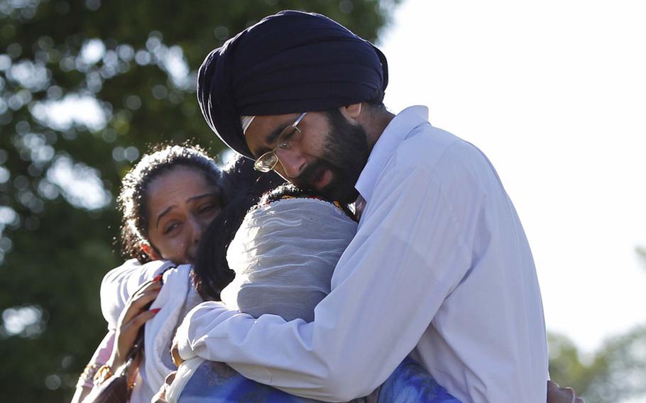 Kanwardeep Singh Kaleka, right, hugs an unidentified woman while his sister Simran Kaleka, left, hugs another unidentified relative, Monday, August 6, 2012, as they meet and mourn the loss of their uncle Satwant Singh Kaleka, president of the Sikh temple, who died in Sunday's temple shootings in Oak Creek, Wisconsin.