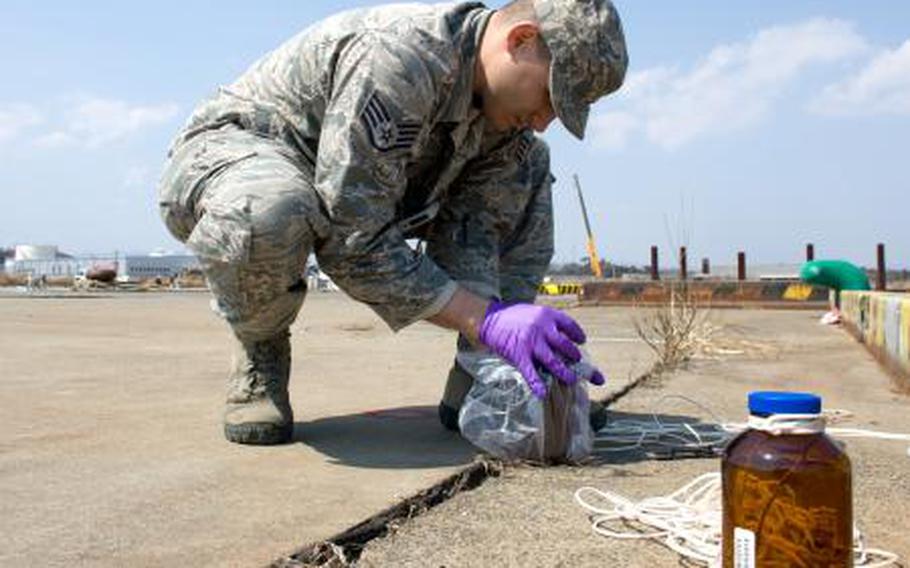 Staff Sgt. Kevin Rivera, Air Force Radiation Assessment Team, collects seawater sample at Onahama port, Fukushima prefecture, March 29. 