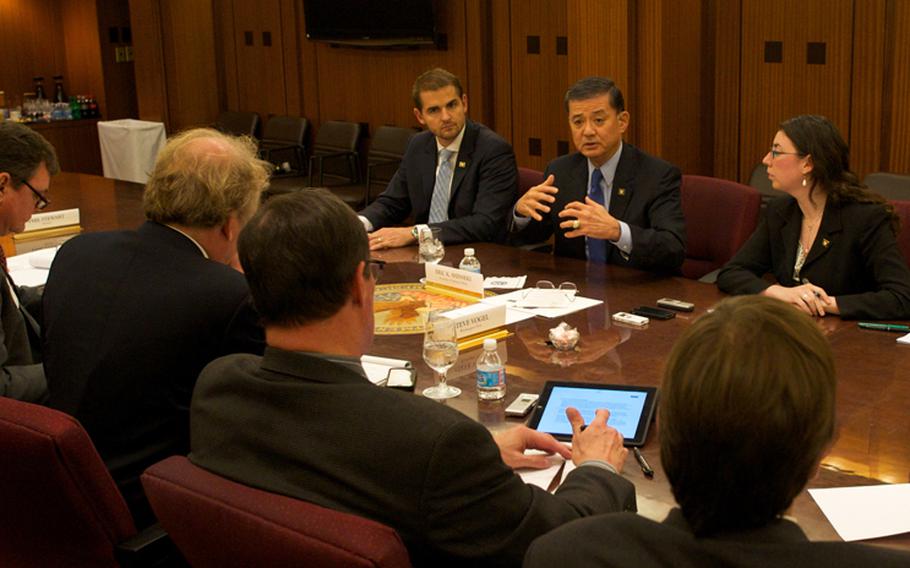 Veterans Affairs Secretary Eric Shinseki, 5th from left, meets with reporters Thursday, Nov. 7, 2013, to discuss progress made in clearing a backlog of disability claims.