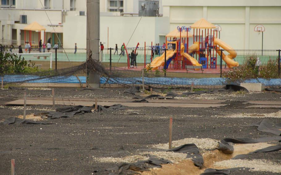 Survey stakes mark the Japanese soccer field where buried drums containing herbicide and dioxin residue were found while children play outside of nearby Amelia Earhart Intermediate School on Kadena Air Base, Okinawa. 