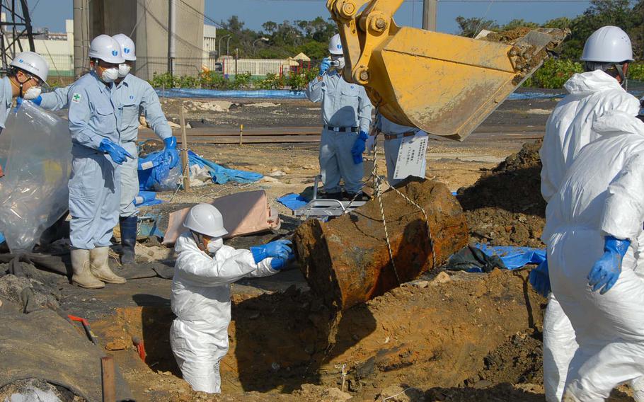 Japan Ministry of Defense workers remove a drum Jan. 28, 2014, from a soccer field next to Amelia Earhart Intermediate School on Kadena Air Base where 22 dioxin- and herbicide-laced drums were unearthed last summer. 
