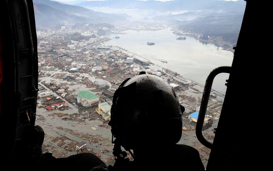 A U.S. sailor, aboard a helicopter deployed from the USS Ronald Reagan, surveys areas affected by the devastating March 2011 tsunami caused by a 9.0 magnitude earthquake.  