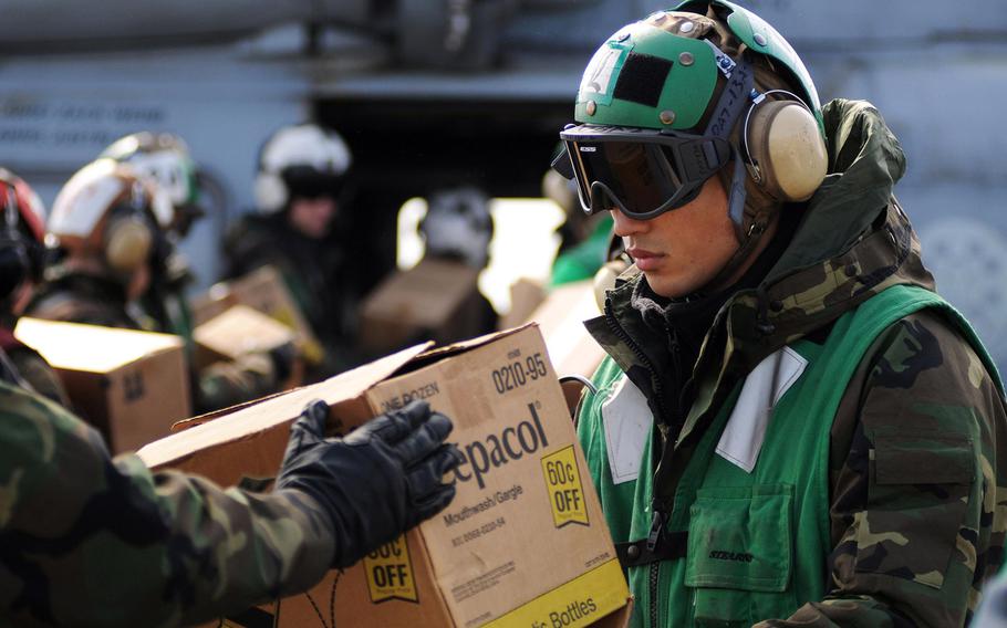 A sailor aboard the USS Ronald Reagan helps load supplies onto an SH-60 Sea Hawk helicopter on March 21, 2011, while at sea off the coast of Japan where the the aircraft carrier was operating to provide humanitarian assistance in support of Operation Tomodachi.