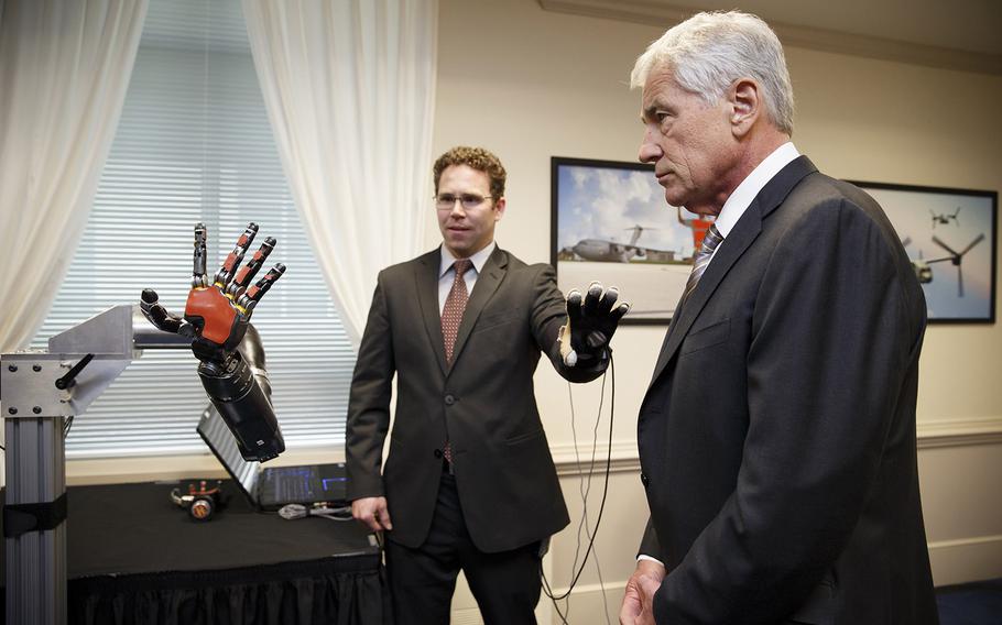 Defense Secretary Chuck Hagel, right, gets a look at the latest high-tech projects being developed for wounded soldiers by the Defense Advanced Research Projects Agency, DARPA, including a robotic hand demonstrated by Matthew Johannes, a senior engineer with DARPA, Tuesday, April 22, 2014, at the Pentagon.