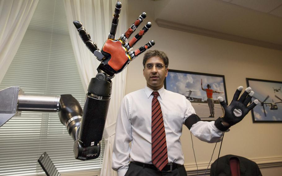 Kapil D. Katyal, an engineer at Johns Hopkins, demonstrates a robotic hand as the Defense Advanced Research Projects Agency, DARPA, displays the latest high-tech projects being developed for wounded soldiers,  Tuesday, April 22, 2014, at the Pentagon. Defense Secretary Chuck Hagel examined the DARPA prototypes, including a full-sized robot named ATLAS.