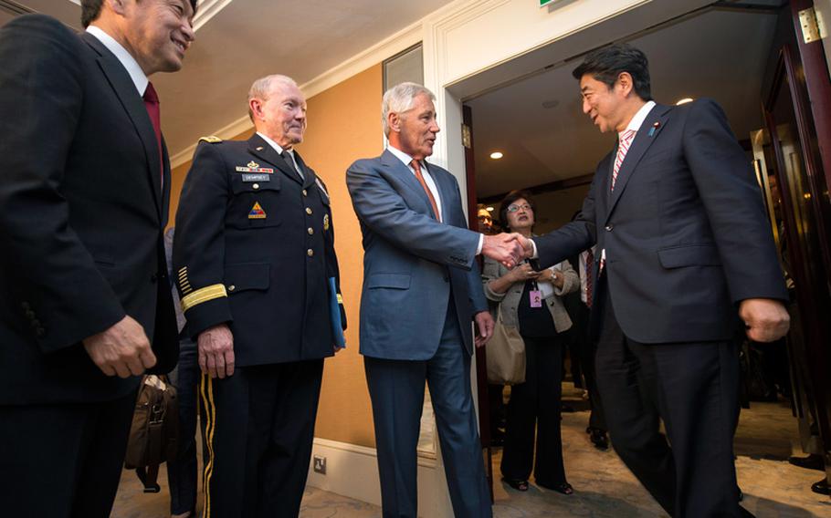 Defense Secretary Chuck Hagel, center, and Army Gen. Martin E. Dempsey, left, chairman of the Joint Chiefs of Staff, greet Japanese Prime Minister Shinzo Abe at the Shangri-La Hotel in Singapore, on Friday, May 30, 2014.