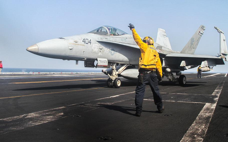 An aircraft handler directs the pilot of an F/A-18 Hornet to the catapult of the USS George H.W. Bush, underway in the Persian Gulf, Aug. 11, 2014.