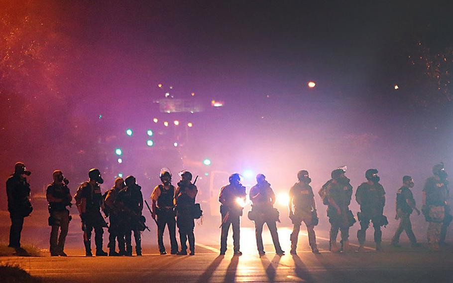 Tactical officers work their way north on West Florissant Avenue in Ferguson, Mo., clearing the road of residents, on Wednesday, Aug. 13, 2014.