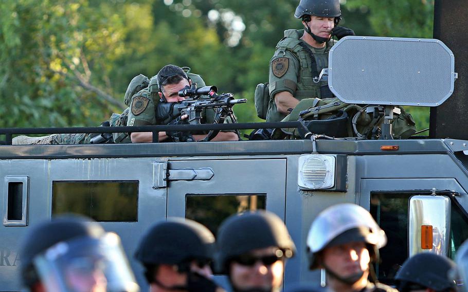 A police sharpshooter keeps an eye on protesters along W. Florissant Avenue on Tuesday, Aug. 12, 2014, in Ferguson, Mo.