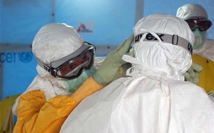 From left, Dr. Joel Montgomery, a team leader with the U.S. Centers for Disease Control and Prevention, adjusts a colleague's personal protective equipment Sept. 17, 2014, before entering the Ebola virus treatment unit in Monrovia, Liberia, during United Assistance, a response to the 2014 West African Ebola outbreak. The outbreak also affected Sierra Leone, Guinea and Nigeria. United Assistance is a U.S. Army Africa-led operation to provide command and control, logistics, training and engineering support to the U.S. government's efforts to contain the Ebola virus outbreak in West African nations. 