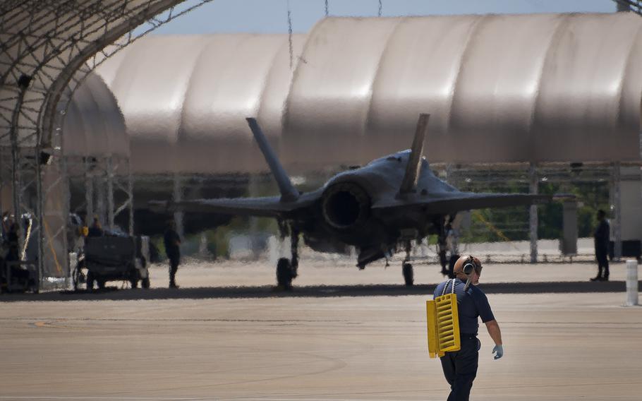 A Lockheed Martin maintainer for the Naval F-35C Lightning II carries wheel chocks back to a hangar after a refueling session at Eglin Air Force Base, Fla. on May 6, 2014. 