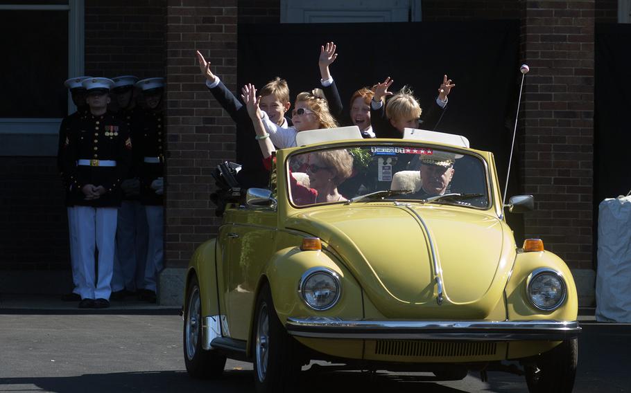 General Amos waves goodbye with his wife and grandchildren as he pulls out of the Marine Barracks in his vintage Beetle in Washington, D.C., following the Passage of Command ceremony on Oct. 17, 2014