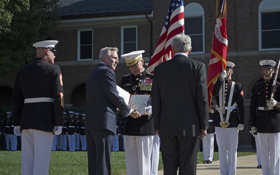 General Amos receives an award for his service and dedication to the military during the Passage of Command at the Marine Barracks in Washington, D.C., on Oct. 17, 2014, from Secretary of the Navy Ray Mabus. Next to Mabus on his right, with his back turned, is Secretary of Defense Chuck Hagel.