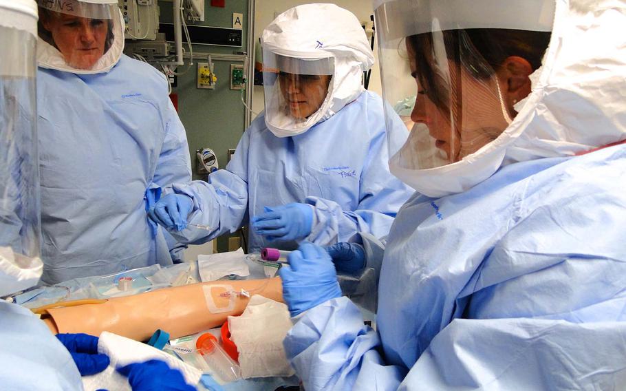 Members of a military medical team training to deploy in the event civilian hospitals need their help treating Ebola patients in the U.S. practice inserting an IV and properly disposing of contaminated needles Friday, Oct. 24, 2014, at San Antonio Military Medical Center in Texas.