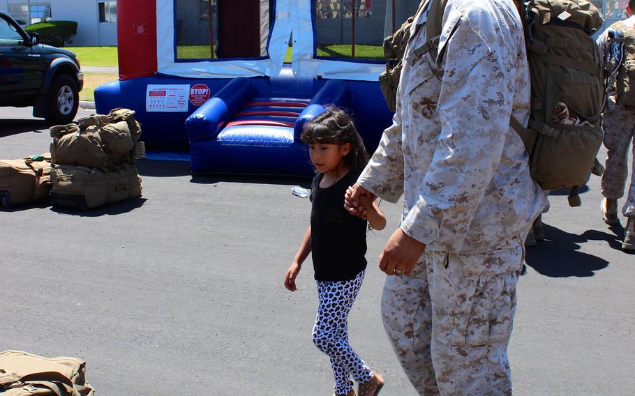 A Marine holds his daughter's hand as he looks for his gear Tuesday, April 14, 2015, at Camp Pendleton, Calif., just after returning from a 7 1/2-month deployment.