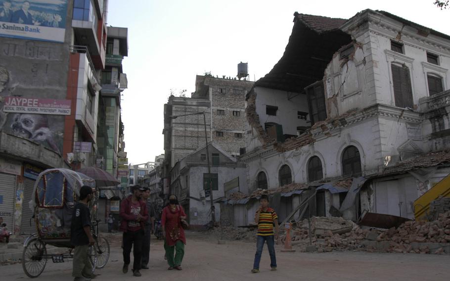Survivors of the earthquake in Nepal walk past damaged buildings in the capital, Kathmandu on Saturday, May 2, 2015. 