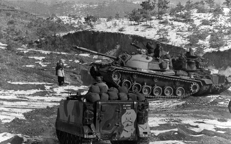 A woman pauses to watch personnel carriers and tanks from the 2nd Battalion, 23rd Infantry Regiment and 1st Battalion, 72nd Armored Regiment that were participating in an exercise on Korea's western front on Dec. 23, 1966. On July 2, 2015, units belonging to the 2nd Infantry Division's 1st Brigade Combat Team will inactivate, marking the end of more than 50 years on the peninsula.