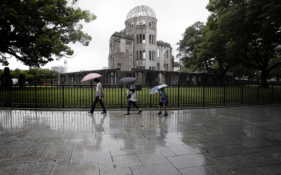 In this July 4, 2015 photo, visitors walk in the rain next to now known as Atomic Bomb Dome in Hiroshima, western Japan. 