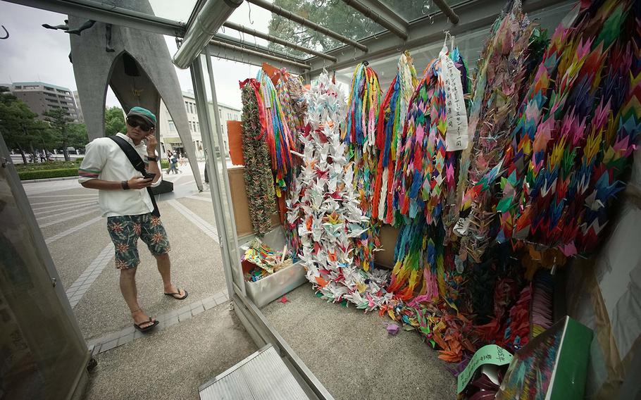 In this July 5, 2015 photo, a visitor stands near the symbolic "Thousand Cranes" near Hiroshima Peace Memorial Museum in Hiroshima, western Japan. 