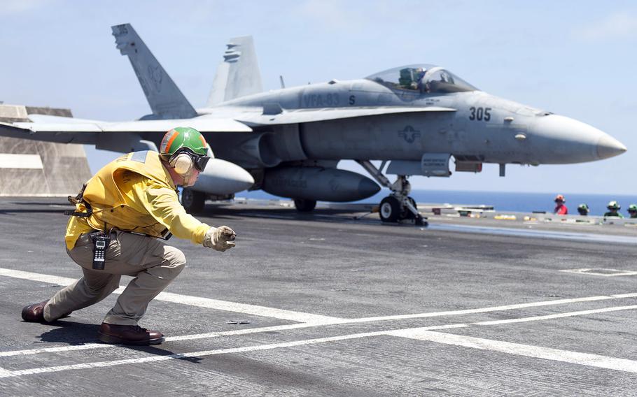 In a June 15, 2015 file photo, Lt. B. J. Burnham signals to launch an F/A-18C Hornet from the flight deck of aircraft carrier USS Harry S. Truman, off the east coast of the United States.