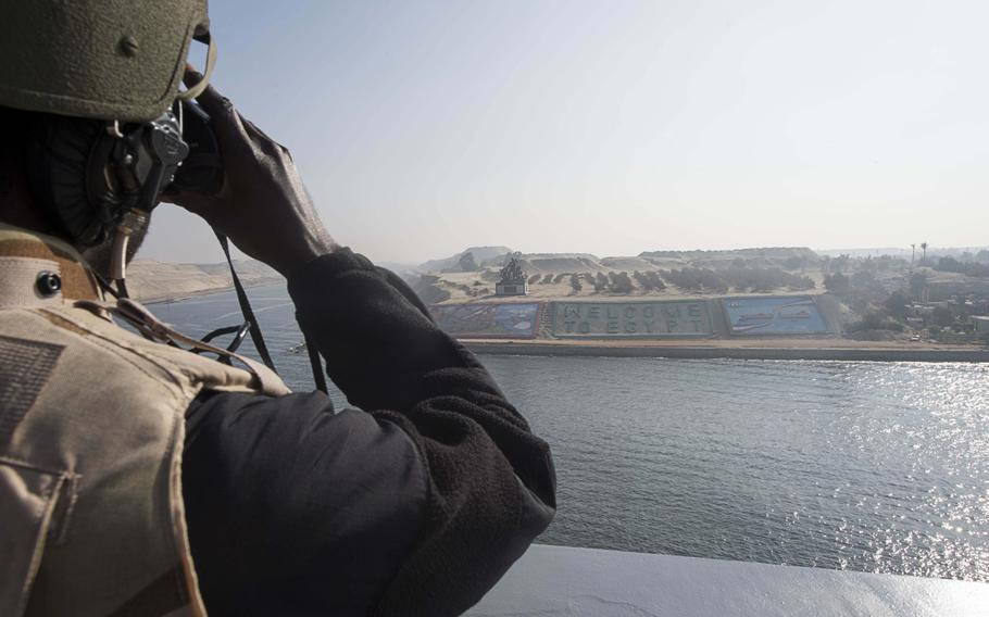 Seaman Ernest Gambrel, from Kumasi, Ghana, looks through binoculars at the "Welcome to Egypt" sign as the amphibious transport dock ship USS Arlington transits the Suez Canal Nov. 9, 2015. 