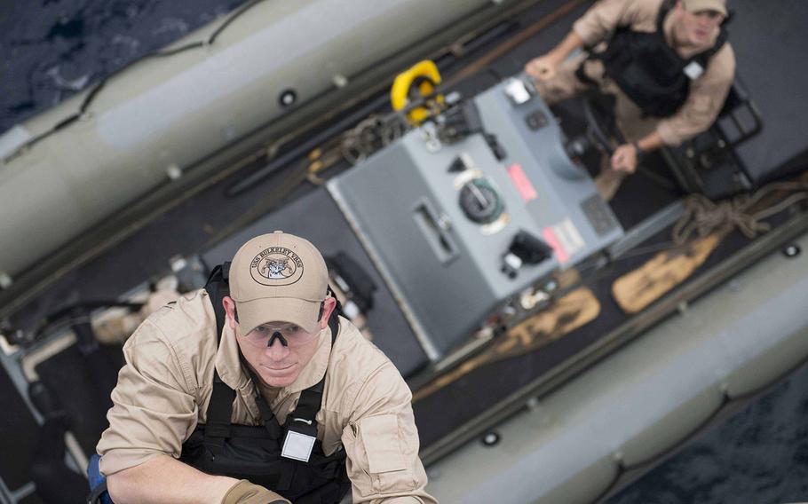 Petty Officer 2nd Class E. Roys, a fire controlman, climbs aboard guided-missile destroyer USS Bulkeley from a rigid hull inflatable boat during a visit, board, search and seizure training exercise Dec. 9, 2015. 