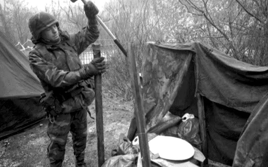 Sgt. Dennis Schaffer of Company A, 2nd Battalion., 68th Armored Regiment, based in Baumholder, Germany, drives an iron pole into the frozen turf while setting up a makeshift toilet at a checkpoint near Olovo, Bosnia-Herzegovina, 45-miles  south of Tuzla in January 1996.