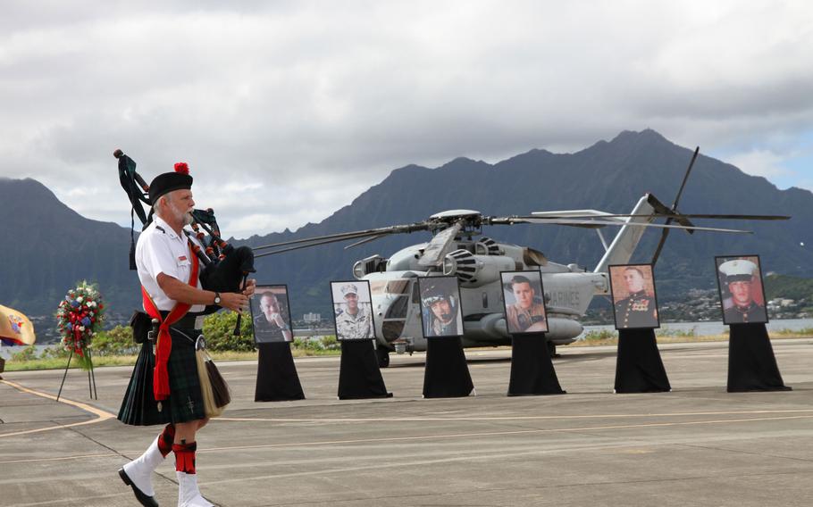 A bagpiper plays 'Amazing Grace' on Jan. 22, 2016, during a memorial at Marine Corps Base Hawaii for 12 Marines killed Jan. 14 when their helicopters crashed north of Oahu. In the background are photos of six of the Marines, whose remains have not been found.
