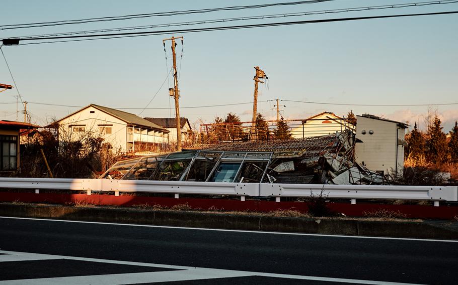 A collapsed building lays on the side of the highway in Futaba, Japan, Feb. 10, 2016. Many damaged buildings that remained standing after the 2011 earthquake have fallen from the years of neglect. 