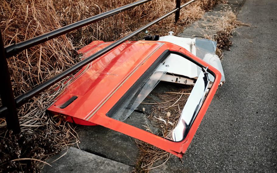 A car door is seen lying on a sidewalk off the highway in Futaba, Japan, Feb. 10, 2016. All of the town's 7,100 residents were evacuated in 2011 and haven't been allowed to return.