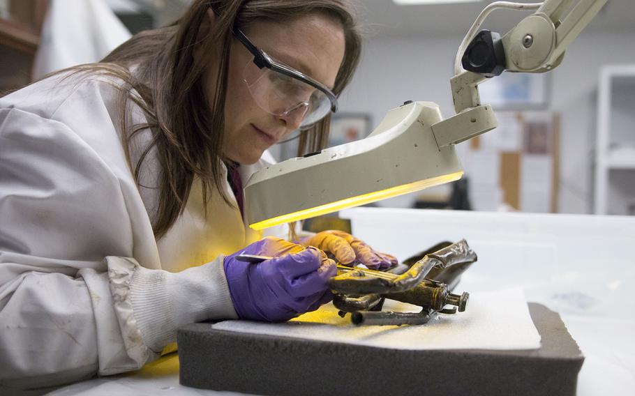 Naval History & Heritage Command lead conservator Shanna Daniel works on an artifact recovered from a 1942 shipwreck.
