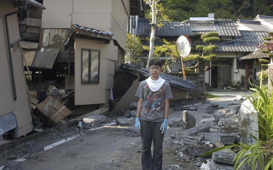 Takumi Hamasaki, 14, stands near earthquake-damaged homes in Mashiki, a small town near the city of Kumamoto, Japan on Tuesday, April 19, 2016. 


