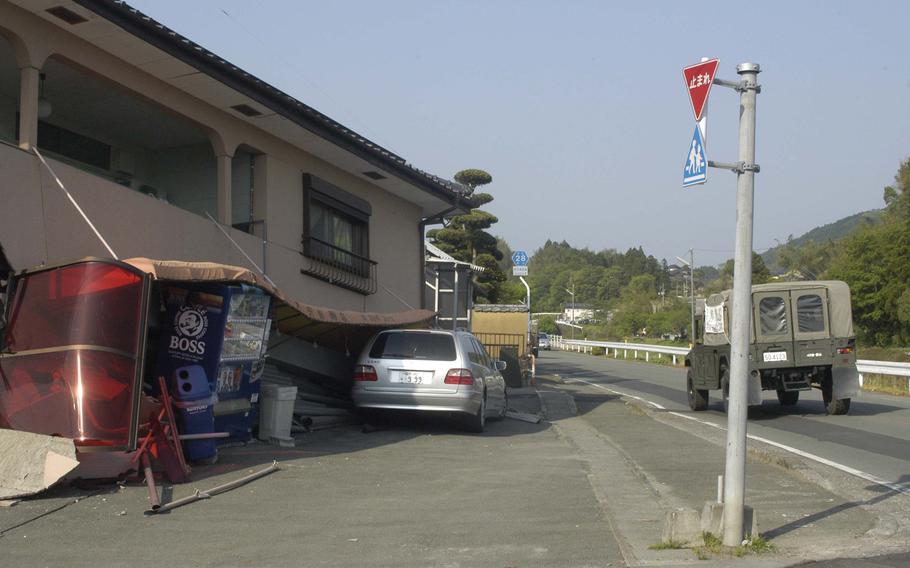 A Japanese Self Defense Force vehicle drives past an earthquake-damaged building near Kumamoto, Japan, on Tuesday, April 19, 2016.  Thousands of Japanese people have been sleeping in the streets since two earthquakes hit the region last week. 


