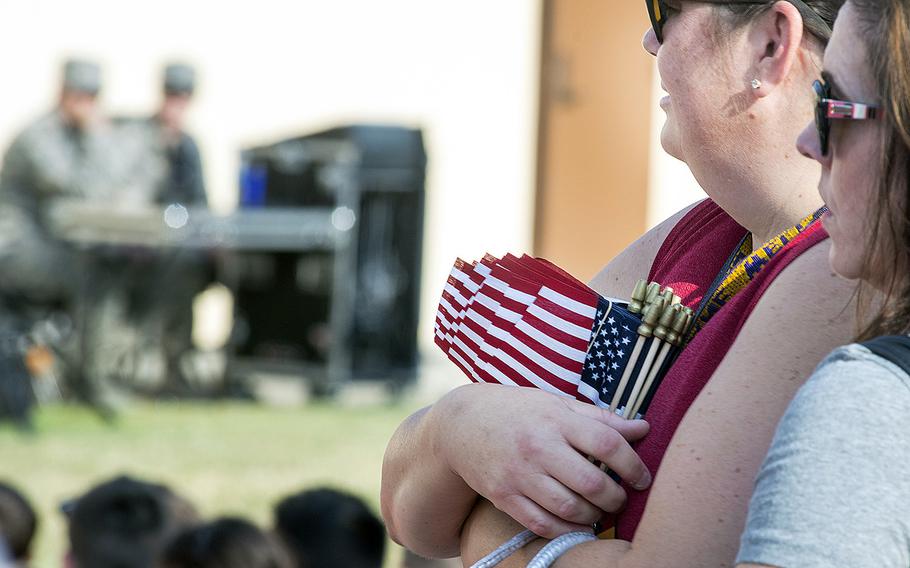 Spectators holding miniature American flags watch as an honor guard at Travis Air Force Base, Calif., perform a flag folding ceremony on Sept. 11, 2015, while a recording of the history of the Stars and Stripes played in the background.