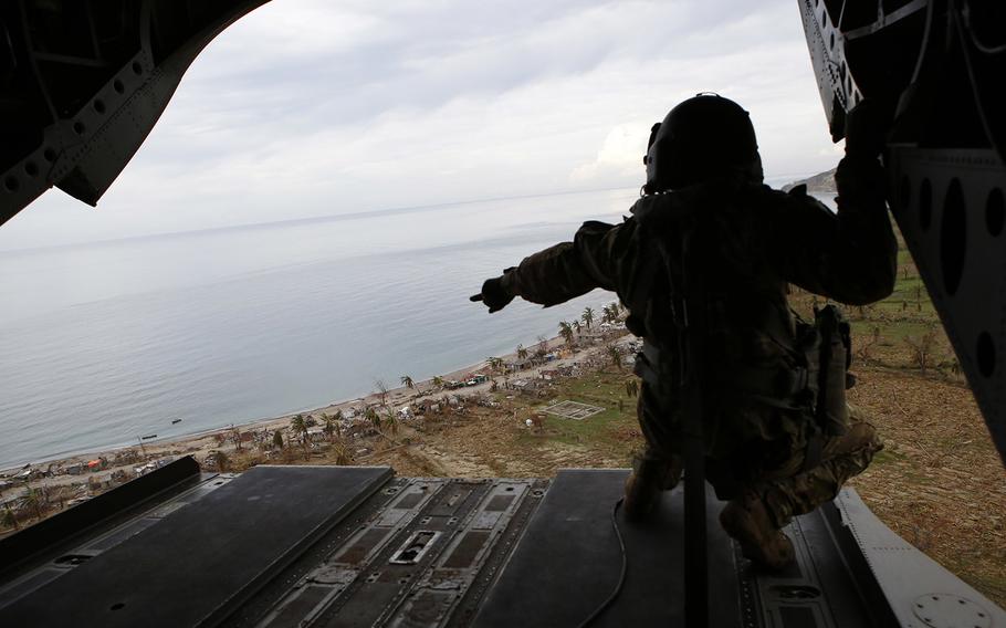 A crew member points to damage left by Hurricane Matthew, from aboard a helicopter near Anse d'Hainault, southwestern Haiti, Friday, Oct. 14, 2016. Two U.S. military helicopters touched down briefly on Friday morning to deliver drinking water and saline to the remote town, which has seen a spike in cholera cases after suffering severe damage from Hurricane Matthew.